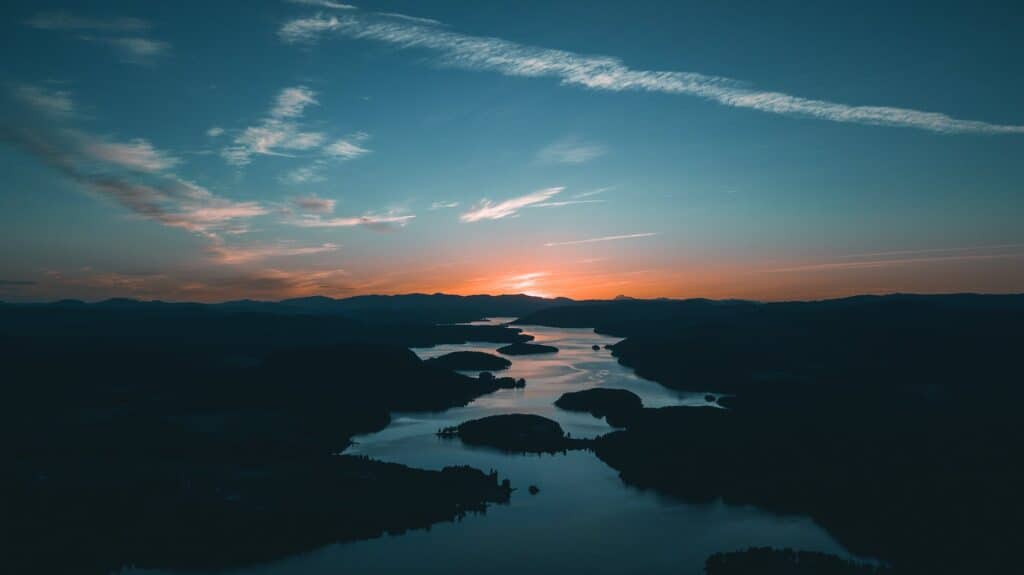 aerial photography of water beside forest during golden hour